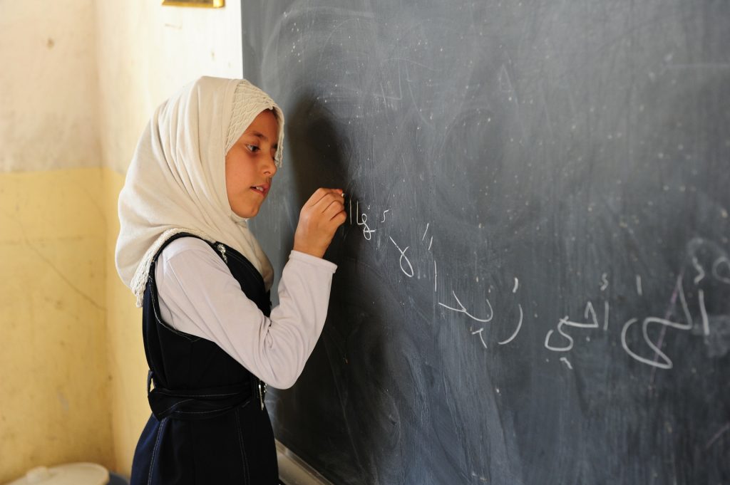 An Iraqi girl writing on a chalkboard